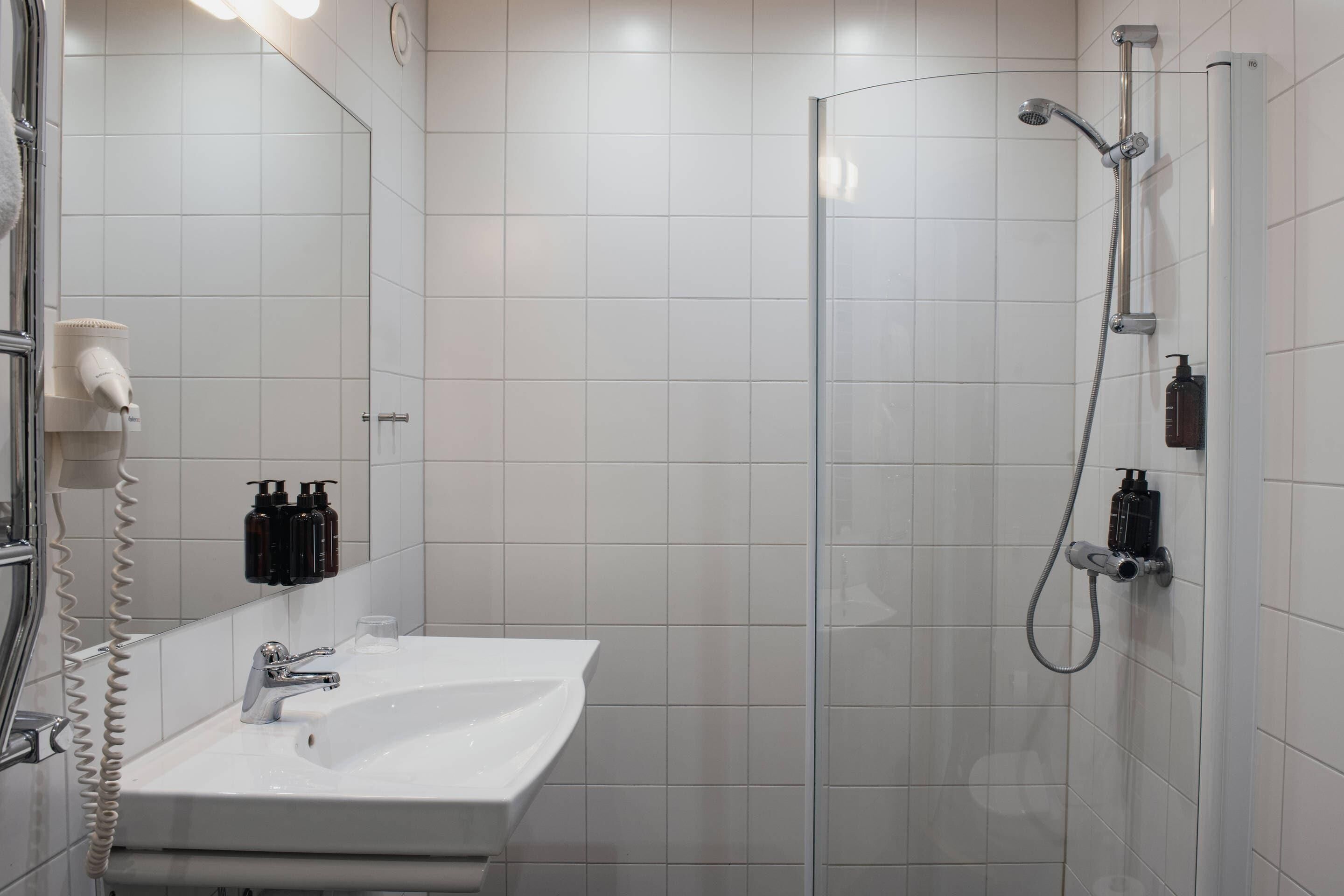 Un baño moderno con ducha de vidrio, lavamanos blanco y espejo.