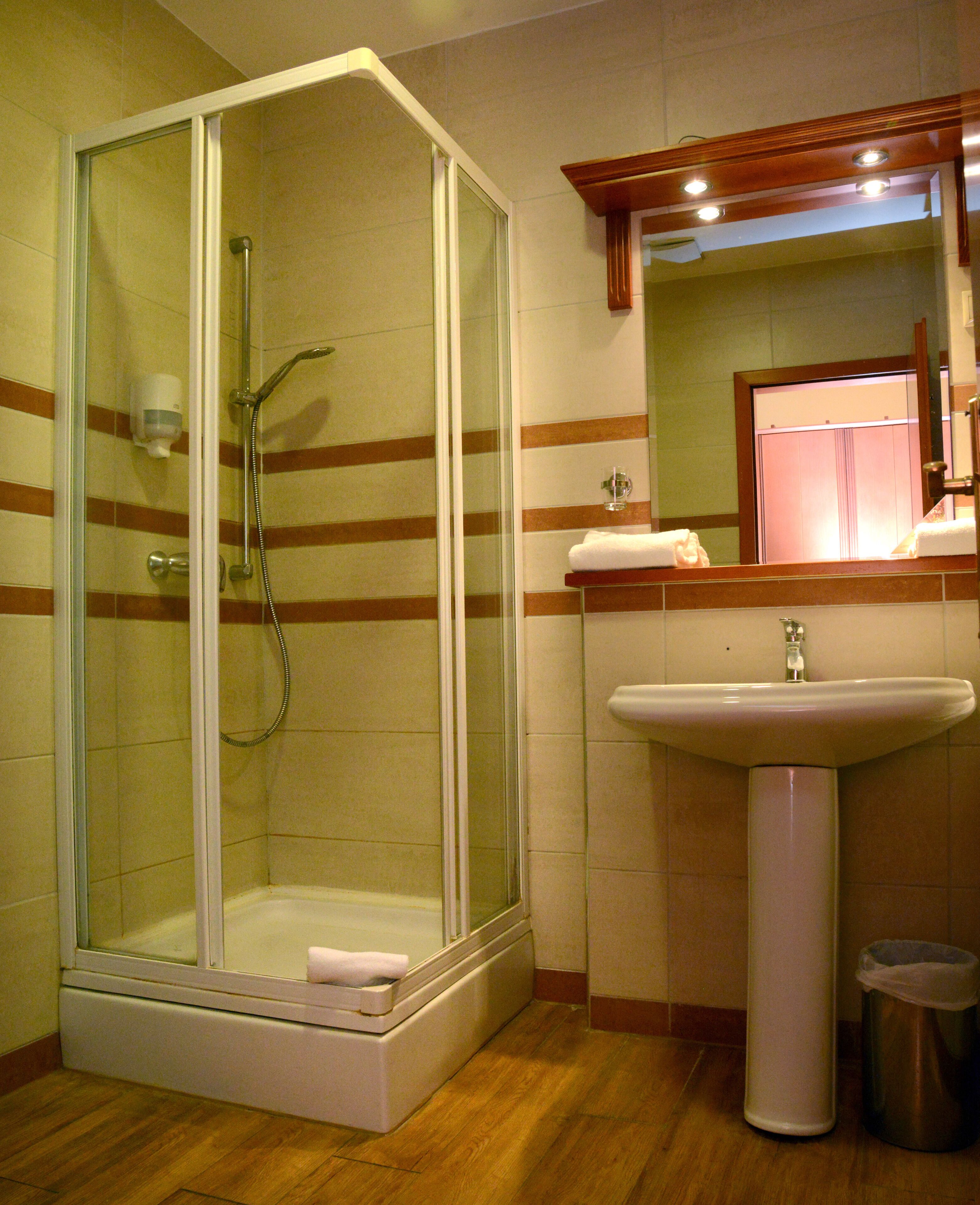 Un baño con ducha envuelta en vidrio, un lavabo y un espejo.