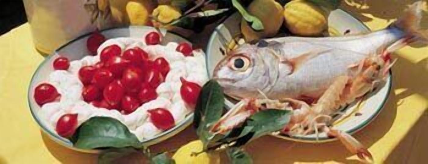Un piatto con un pesce intero e una ciotola di ciliegie rosse su un tavolo giallo.