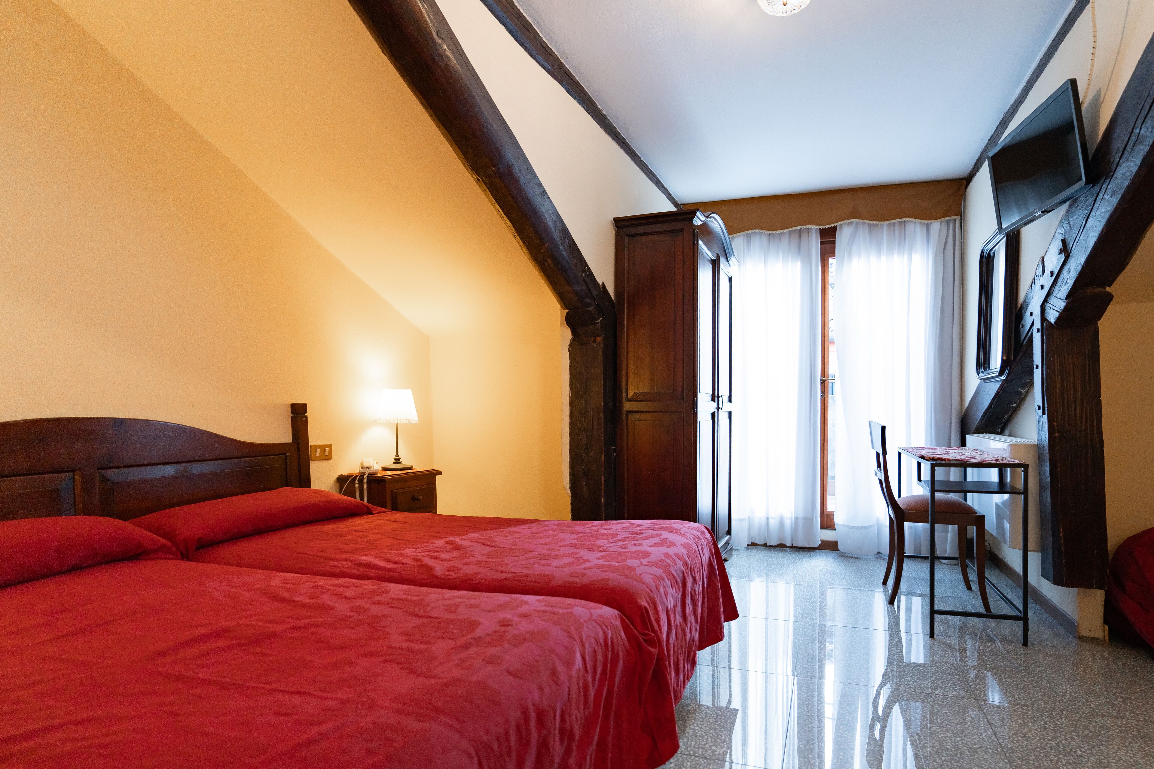 A hotel room with a large bed, a desk, and a chair.
