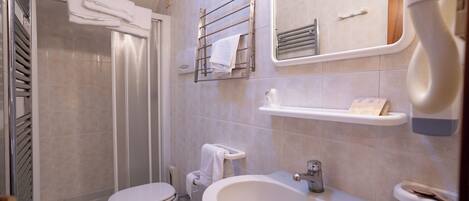 A modern bathroom with a toilet, bidet, sink, and towel rack.