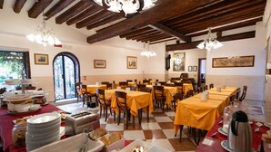 A dining area with tables set for a meal, featuring a checkered floor and wooden beams on the ceiling. - Tivoli Hotel (Venice)