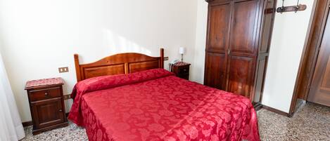 Quarto com cama de madeira, mesa de cabeceira, guarda-roupa e chão coberto por carpete.
