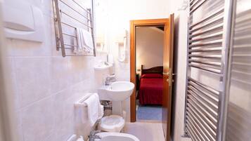 Un bagno compatto con bidet, lavabo e portasciugamani.
