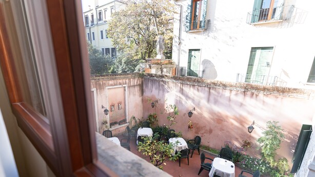 A courtyard with outdoor seating, a statue, and a view of surrounding buildings. - Tivoli Hotel (Venice)