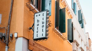 A hotel with a signboard, a window with curtains, and a door. - Tivoli Hotel (Venice)