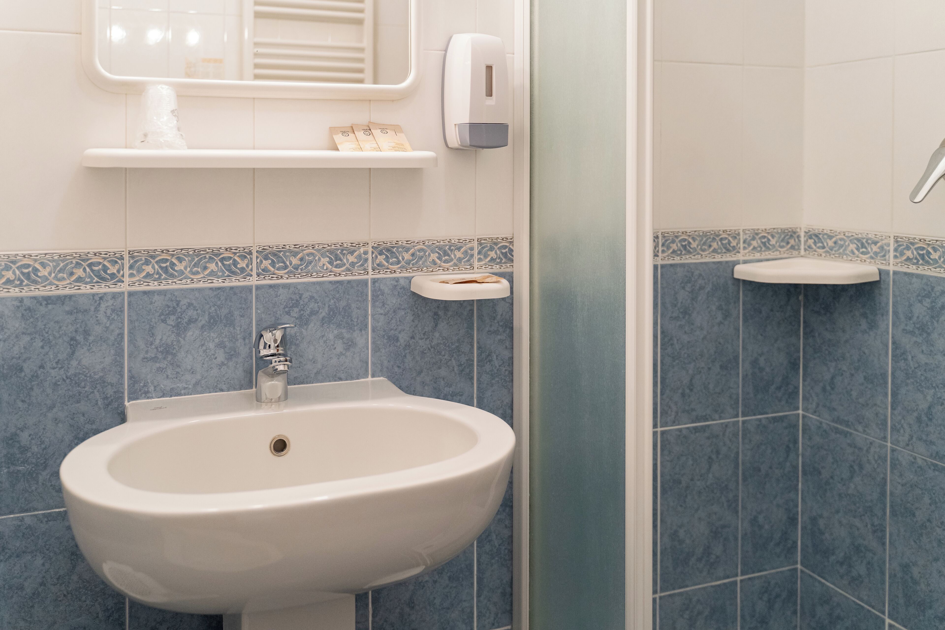 A bathroom with a white sink, a soap dispenser, and a toilet.