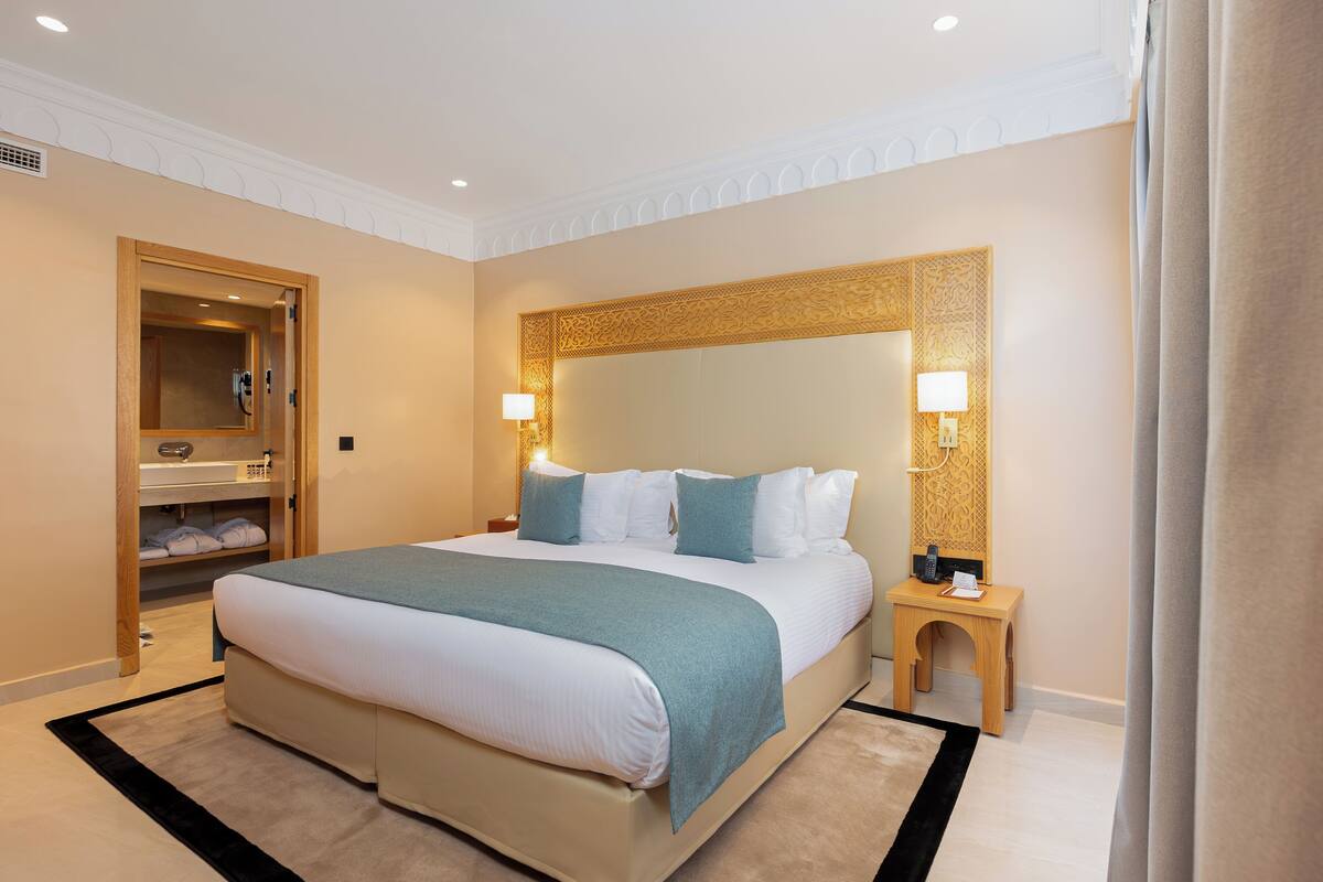 A hotel room with a large bed, bedside lamps, a wooden nightstand, and a built-in wardrobe.