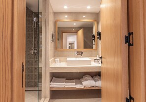 A modern bathroom with a glass-enclosed shower, a large mirror, a sink, and neatly folded towels on a shelf. - Kenzi Azghor (Ouarzazate)