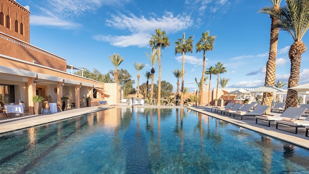 A pool area with clear water, lounge chairs, and palm trees. - Kenzi Azghor (Ouarzazate)