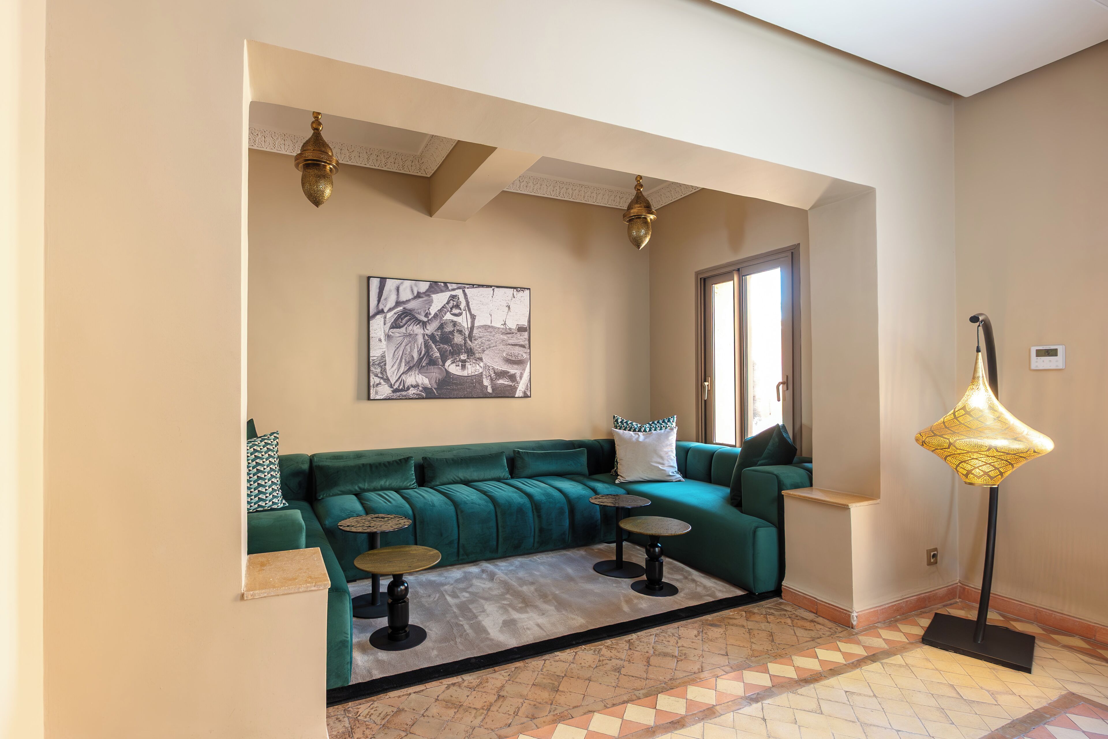 A living room with a teal sofa, two round coffee tables, a floor lamp, and a framed picture on the wall.