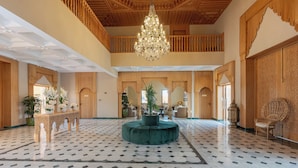 A spacious lobby with a high ceiling, a central green ottoman, a chandelier, and a patterned floor. - Kenzi Azghor (Ouarzazate)