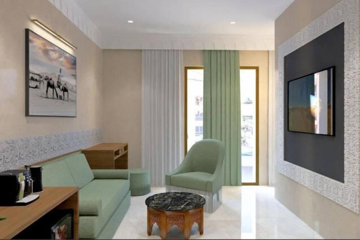 Een moderne woonkamer met een bank, fauteuil, salontafel en een flatscreen televisie aan de muur.
