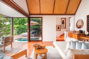 Una habitación moderna con terraza de madera, piscina, sofá y escritorio con espejo.