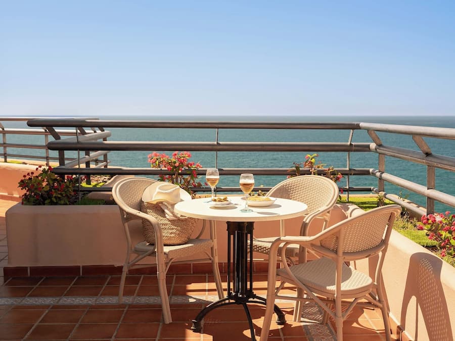 A terrace with a table and chairs, overlooking a body of water.