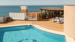 A pool area with a clear view of the sea, lounge chairs, and a covered seating area. - Ona Princesa Playa (Marbella)