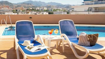 Una piscina al aire libre de temporada, sillones reclinables de piscina