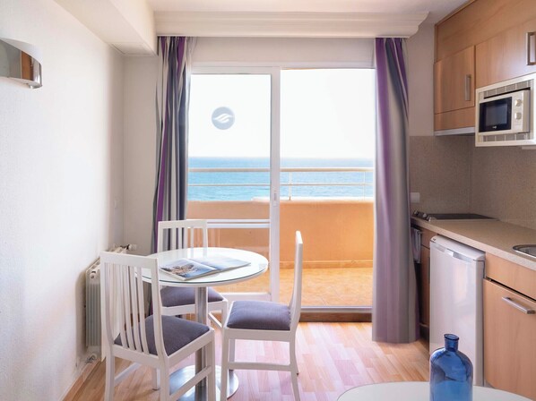 A compact balcony with a view of the sea, a small dining area with a table and chairs, and a kitchenette with a microwave. - Ona Princesa Playa (Marbella)