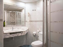 Een badkamer met een marmeren wastafel, toilet en douchecabine.
