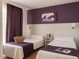 A hotel room with two beds, a nightstand, a wall-mounted painting, and a window with curtains.
