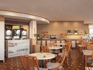 A restaurant with round tables and wicker chairs, a coffee bar with espresso machines, and a brick wall backdrop. - Ona Princesa Playa (Marbella)