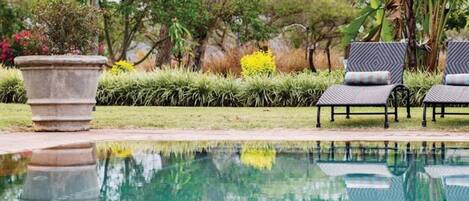 Una piscina al aire libre, sombrillas, tumbonas