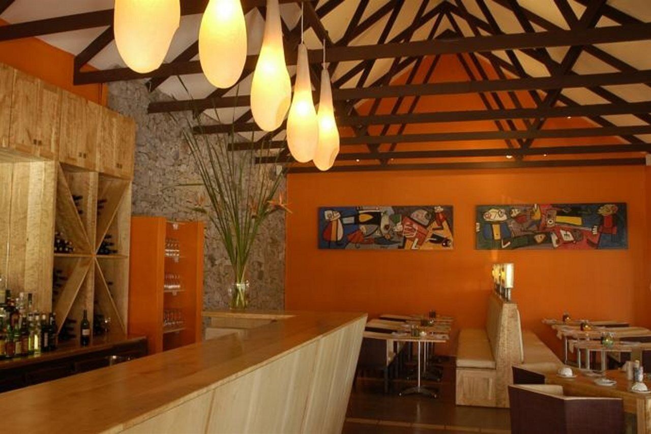 A bar area with wooden shelves, hanging pendant lights, and artwork on the walls.