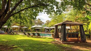 Una piscina al aire libre, sombrillas, tumbonas