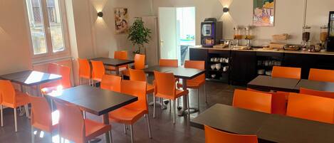 Un espace repas avec des tables et des chaises, un comptoir de cuisine et une plante en pot.
