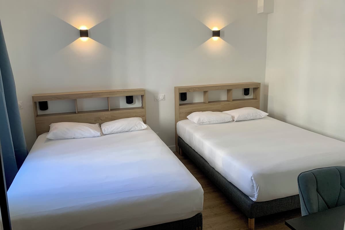 Two single beds with wooden headboards, white bedding, and wall-mounted light fixtures.