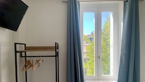 Una habitación con un perchero de madera, un radiador y una ventana con cortinas.