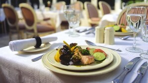 Ein Tisch ist für eine Mahlzeit in einer überdachten Essbereich im Freien gedeckt, mit Stühlen und einer Glaskonstruktion.