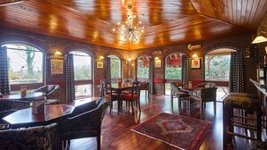 Ein gemütliches Restaurant mit Holzböden, Rundbogenfenstern und einer Kristallleuchter. Tische und Stühle sind zum Essen bereitgestellt.