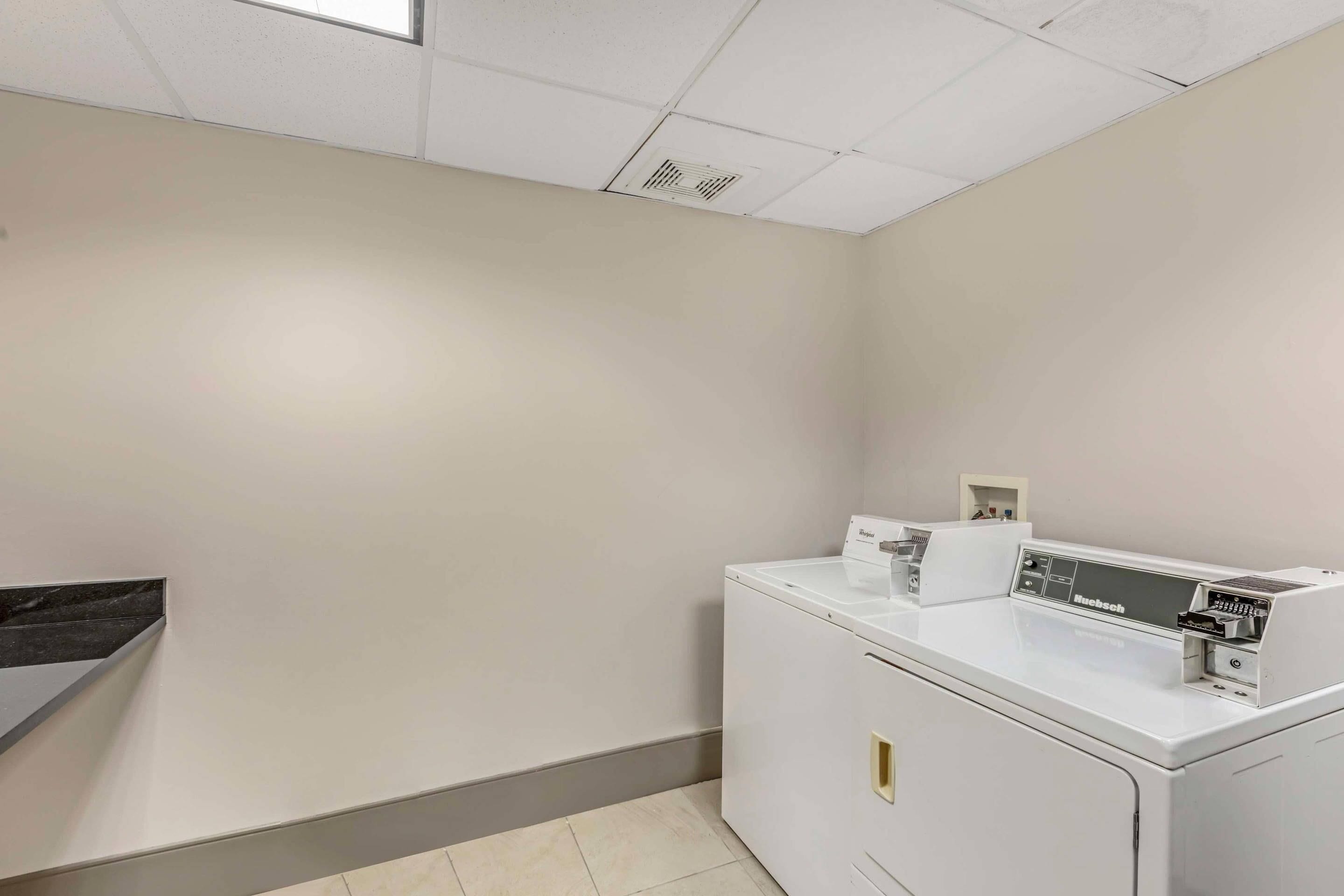 A laundry room with a white washing machine, a dryer, and a small shelf with items.