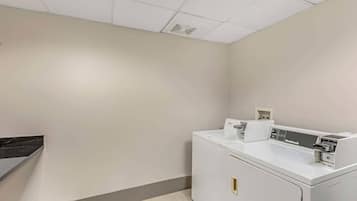 A laundry room with a white washing machine, a dryer, and a small shelf with items.