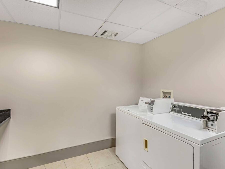 A laundry room with a white washing machine, a dryer, and a small shelf with items.