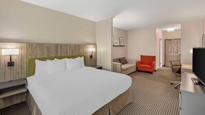 A hotel room with a large bed, a desk with a computer, a chair, and a small table.