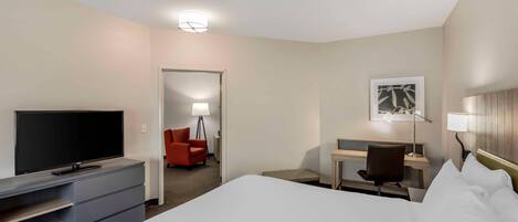 A hotel room with a bed, a desk, a chair, a television, and a lamp.