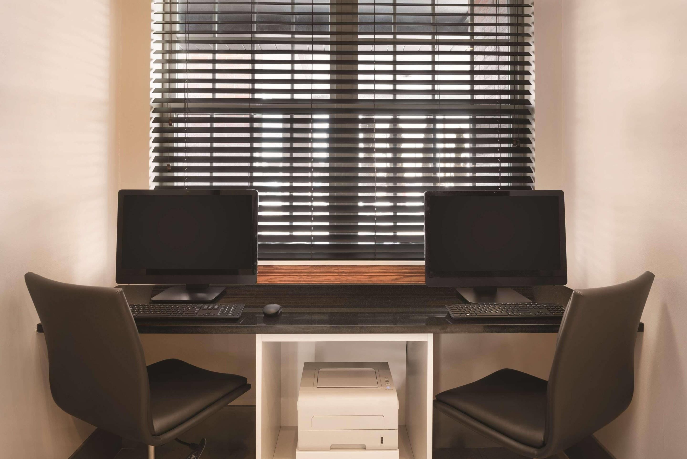 A workspace with two monitors, a keyboard, a mouse, and a printer on a desk.