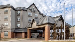 A multi-story hotel with a modern design, featuring a prominent entrance with a covered area and a sign that reads 'Country Inn & Suites.'