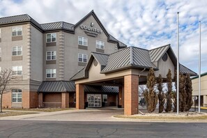 A multi-story hotel with a modern design, featuring a prominent entrance with a covered area and a sign that reads 'Country Inn & Suites.'