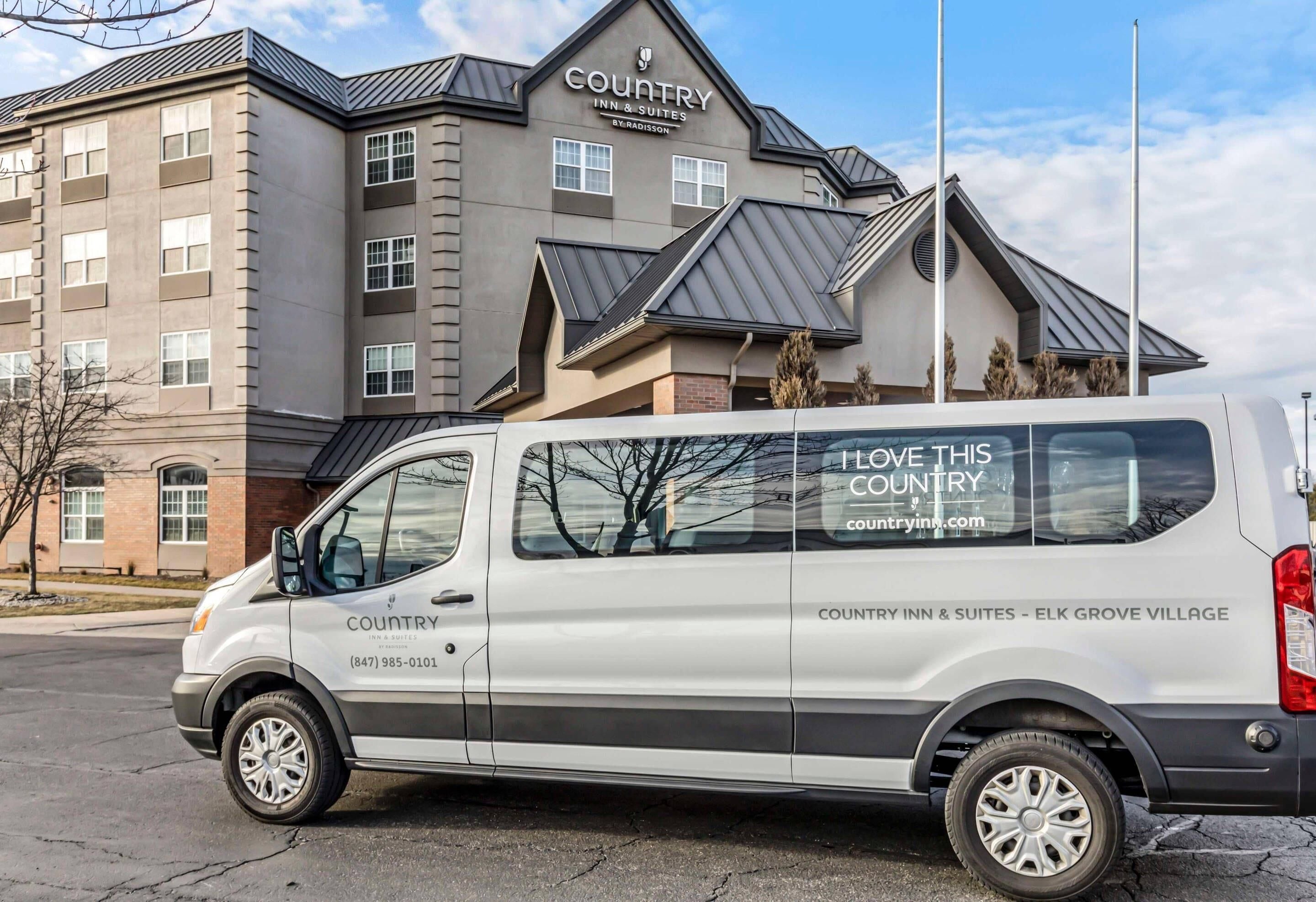A white van parked in front of a building with a sign reading 'COUNTRY INN & SUITES' and a website address 'countryinn.com'.