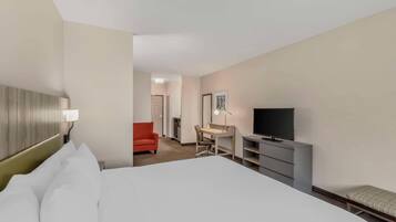 A hotel room with a bed, a desk, a television, and a red chair.