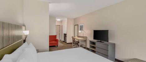 Una habitación de hotel con cama, escritorio, televisor y una silla roja.