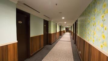 Un pasillo con puertas a la izquierda, una alfombra estampada y papel tapiz floral a la derecha.