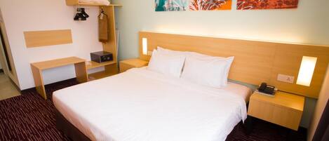 Habitación de hotel con una cama grande, mesitas de noche, un armario y cuadros en la pared.