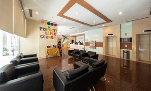 A modern reception area with a reception desk, black leather seating, and a wall with colorful letters spelling "PRESCOTT SELFIE CORNER". - Prescott Hotel KL Medan Tuanku (Kuala Lumpur)