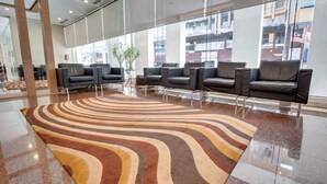Um lobby moderno com carpete listrado, assentos de couro e grandes janelas.