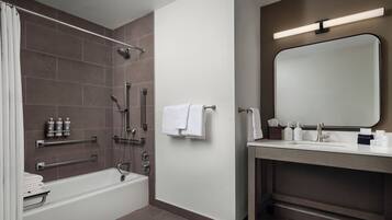 A modern bathroom with a bathtub, shower, and vanity with a mirror.