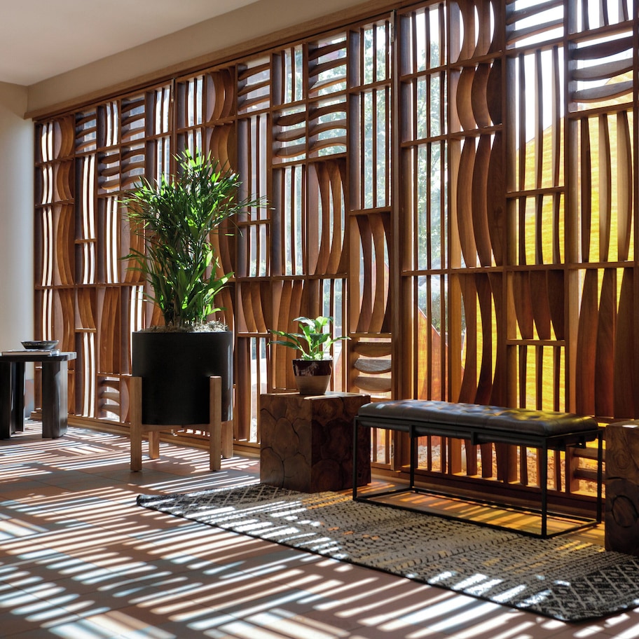 A room with a wooden partition, a bench, and potted plants.